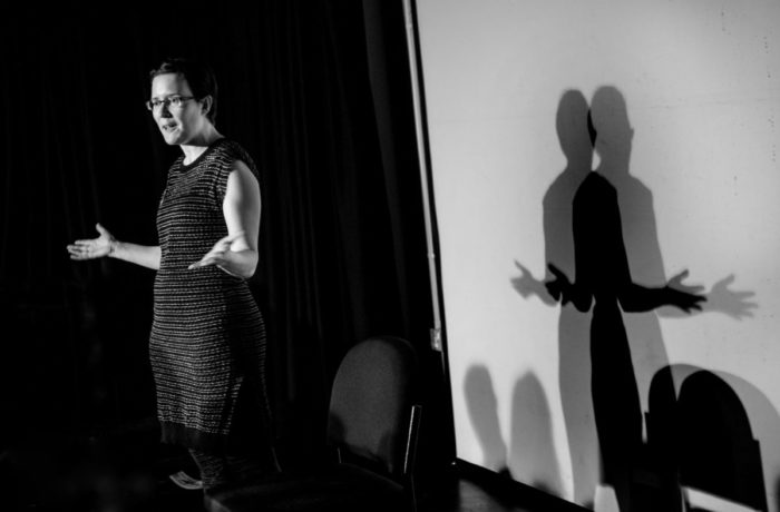 black and white shot of a single presenter silhouetted against a white screen