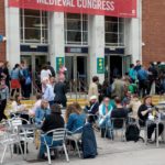 Delegates sit in groups on tables outside the redbrick Students' Union building.