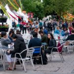 A group of delegates of various ages sat at tables on the main University Square plaza