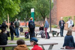 Many delegates sat or stood around benches chatting and smiling near Esther Simpson Building on The University of Leeds Campus.