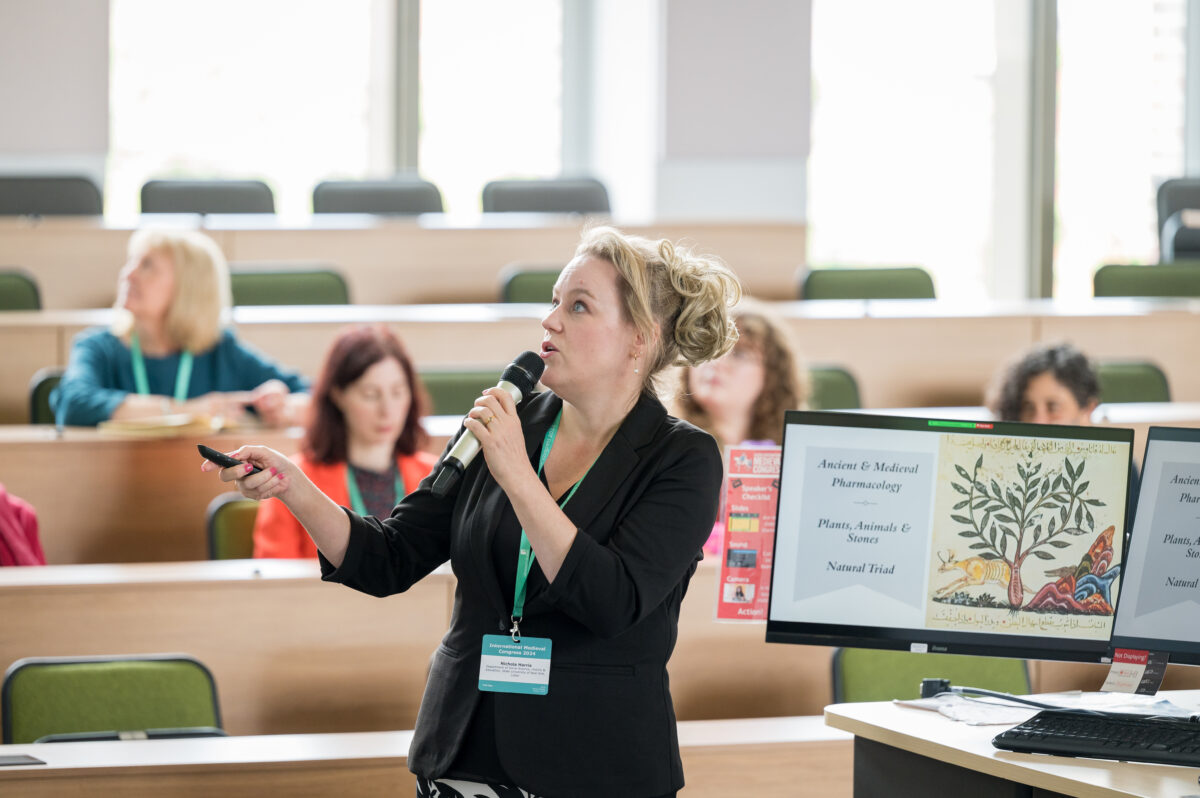 A delegate speaks into a microphone as they present their paper.