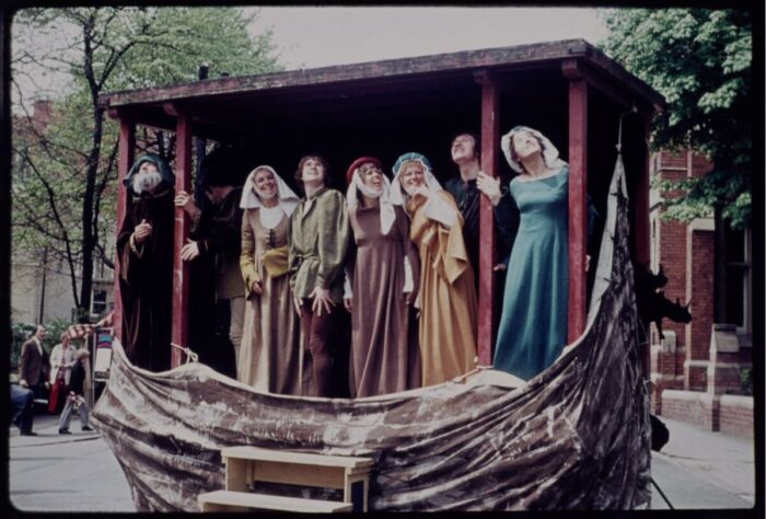 Actors playing Noah and his family gaze up to the heavens smiling. The moveable stage has been dressed to look like an ark.