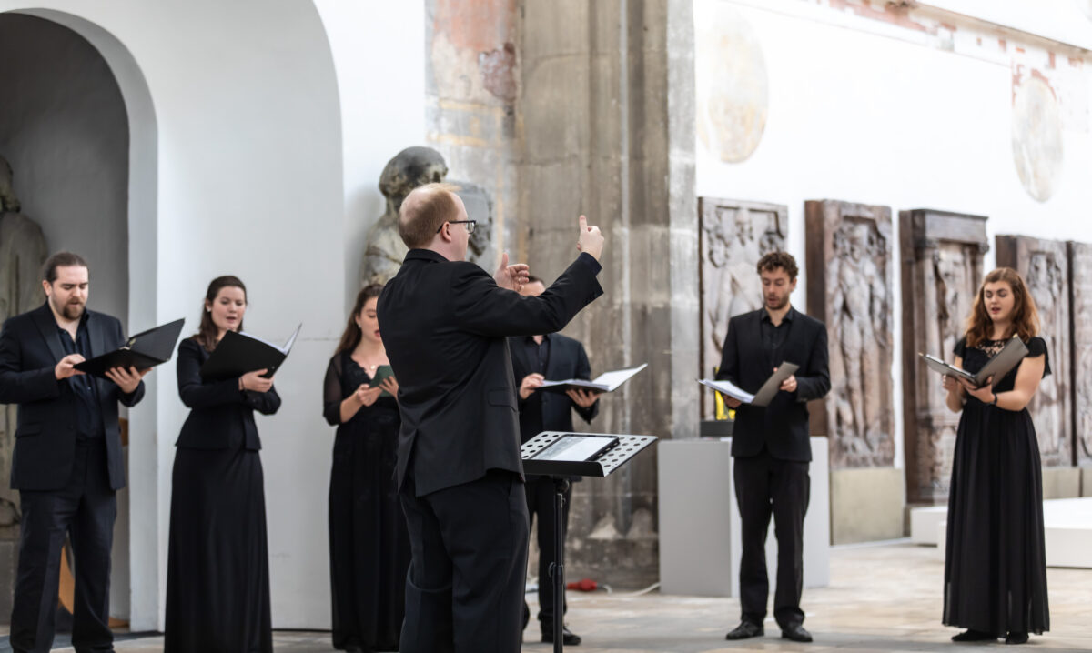 A choir director directing a choir who are dressed in black.