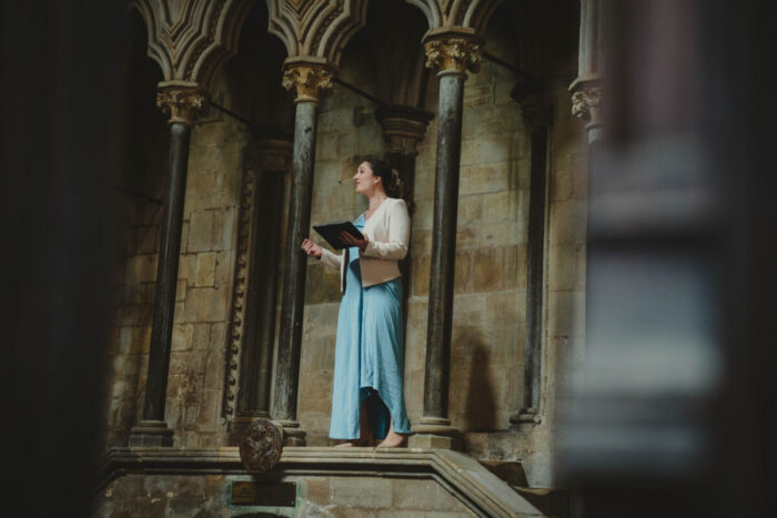 A singer in a blue dress singing in a religious building.